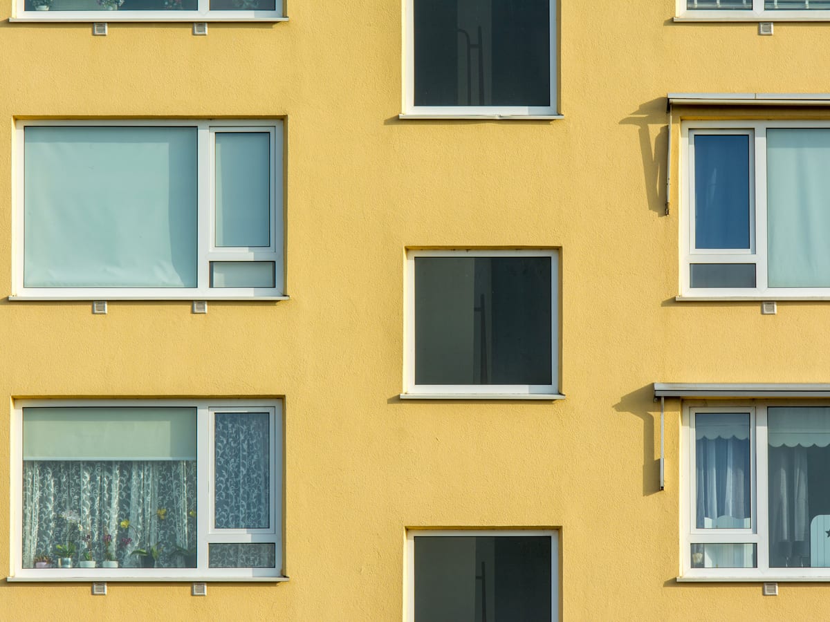 Close-up view of a yellow apartment building facade with windows and balconies.